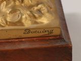 a close up of a gold statue on a white surface