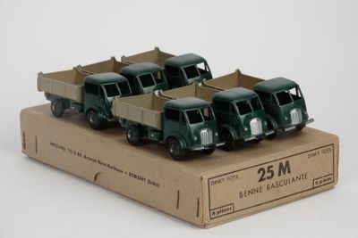 four toy trucks in a cardboard box on a white surface