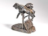 statue of a horse and rider jumping over a wooden fence