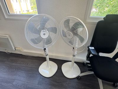 two chairs and a fan in the corner of a room