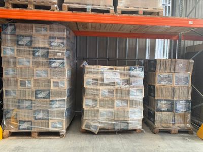 Plusieurs palettes de cartons sont empilées sur une palette dans un entrepôt.