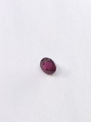 un gros plan d'une pierre rouge sur une surface blanche