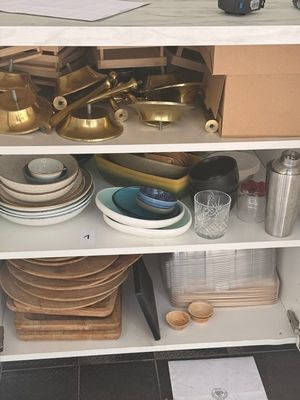 une étagère blanche sur laquelle sont posés tout un tas de plats et d'ustensiles