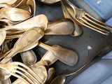 a lot of silver spoons and forks on a tray