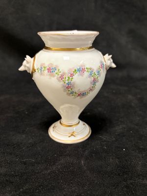 un vase blanc orné d'un motif floral sur fond noir