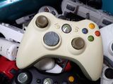 a white controller sitting on top of a pile of other video game controllers