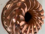 un moule à gâteau en métal posé sur une table avec un fond blanc