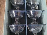 six empty wine glasses in a blue box on a table