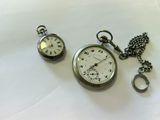 a silver pocket watch and a silver pocket watch on a white surface