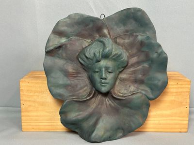 une sculpture représentant le visage d'une femme sur une feuille