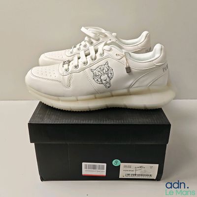 quelqu'un porte une chaussure blanche avec un lion sur le côté