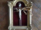 un crucifix dans un cadre doré posé sur un plancher en bois