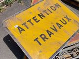 a yellow sign sitting on top of a pile of wood
