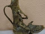 a bronze statue of a woman sitting on top of a vase