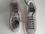 pair of grey sneakers with laces on them on a white surface