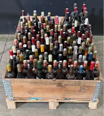 de nombreuses bouteilles de vin dans une caisse en bois posée par terre