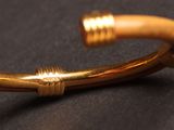 a close up of a gold bracelet on a black surface