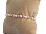 a cushion with a pillow and a bracelet with pearls on it