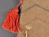 a brown bag with a red tassel on top of it