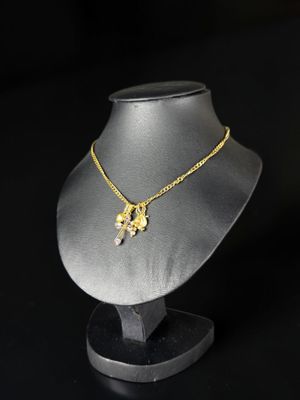 un collier en or posé sur un socle de mannequin, sur fond noir