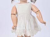 an old fashioned doll with a white dress and brown shoes