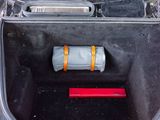 the trunk of a red car with a bag in the trunk