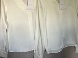pair of white blouses hanging on a hanger in a clothing store