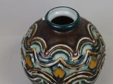 a brown and blue vase sitting on a white surface