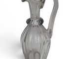 a clear glass pitcher with a handle on a white surface