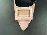 beige pointed - toeed shoes with a buckle on a black surface
