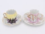 pair of porcelain cups and saucers decorated with flowers on a white background