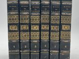 six vieux livres sont alignés sur une surface blanche