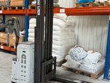 a forklift in a warehouse with a lot of boxes on the shelves