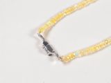 a close up of a yellow beaded necklace on a white surface