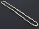 gros plan d'un collier de perles blanches sur une surface noire
