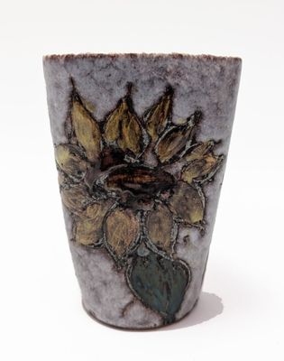 a vase with a sunflower on it on a white surface