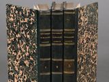 three books are stacked on top of each other on a gray surface