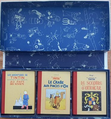 trois livres dans une boîte bleue posée sur une table en bois