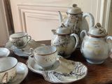 a table with a tea pot, cups and saucers on it