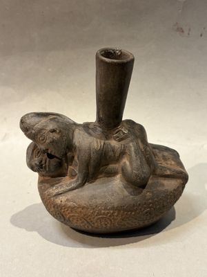a small vase with a dog on it on a table