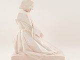 statue of a woman in a white dress sitting on a white surface