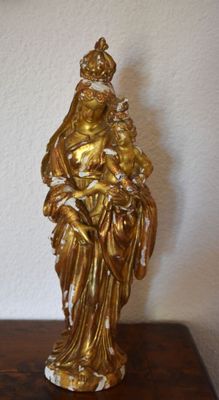 gold statue of a woman holding a child on a wooden table