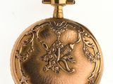 a gold pocket watch on a white surface with a white background