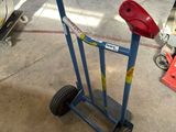 un diable bleu avec une poignée rouge dans un garage
