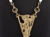 un collier plaqué or représentant une femme tenant une perle