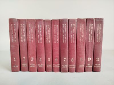 six livres rouges sont alignés sur une surface blanche