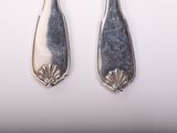 pair of silver spoons on a white surface with a white background