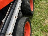 a tractor that is sitting in the grass with it ' s wheels down