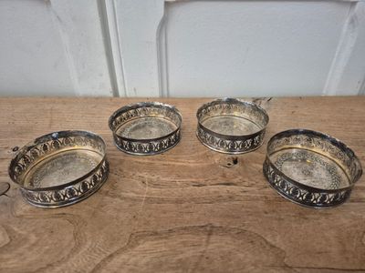 four silver plated ashtrays on a wooden table