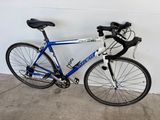 un vélo bleu et blanc appuyé contre un mur blanc
